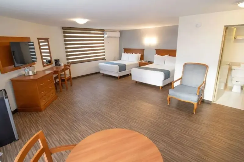 Une chambre lumineuse avec deux lits et un coin salon.