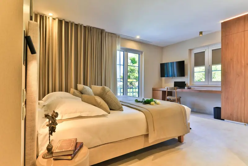 Une chambre lumineuse avec un grand lit et un bureau près d'une fenêtre.