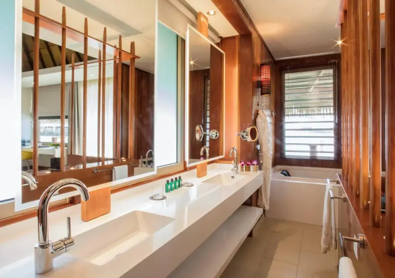 Une salle de bain lumineuse avec deux vasques et une baignoire.