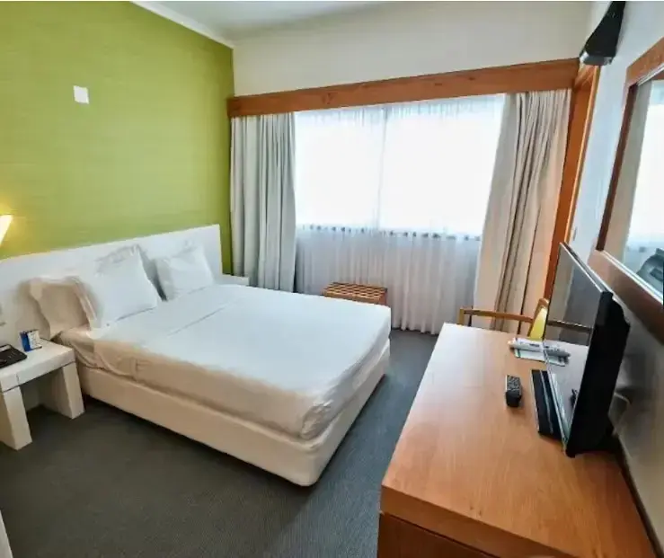 Une chambre lumineuse avec un grand lit et un bureau.