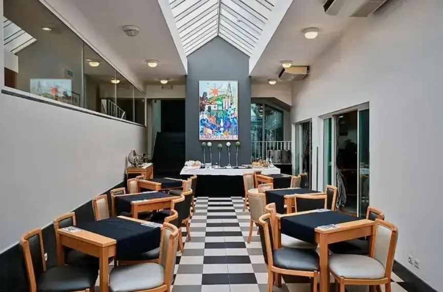 Une salle de restaurant avec des tables et des chaises disposées sur un sol à carreaux.