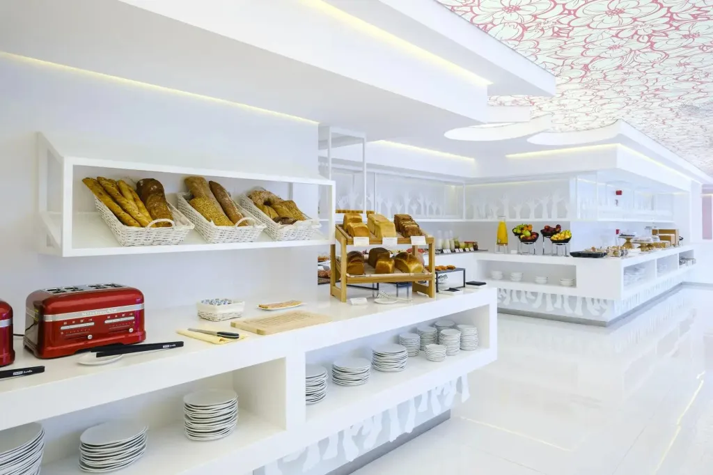 Un buffet propose une variété de pains et de pâtisseries dans une salle lumineuse.