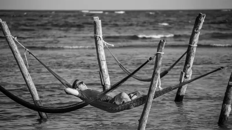 Un homme se détend dans un hamac au bord de l'eau.