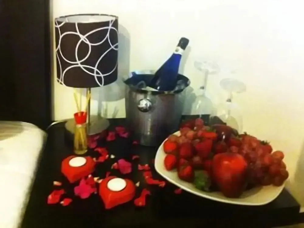 Une table basse présente une bouteille de champagne, des fruits frais et des bougies.