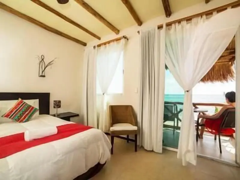 Une chambre lumineuse avec un lit recouvert d'une courtepointe rouge et une vue sur la mer.