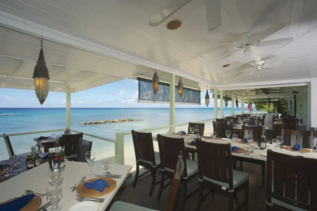 Une salle à manger lumineuse offre une vue dégagée sur la mer turquoise.