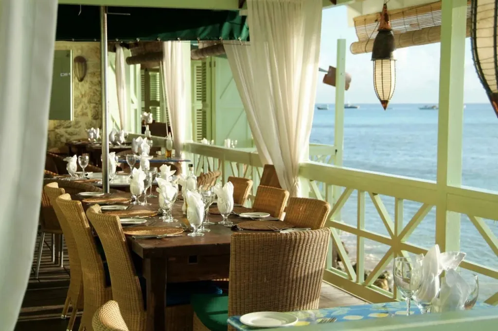 Une longue table est dressée pour un repas en terrasse avec vue sur la mer.