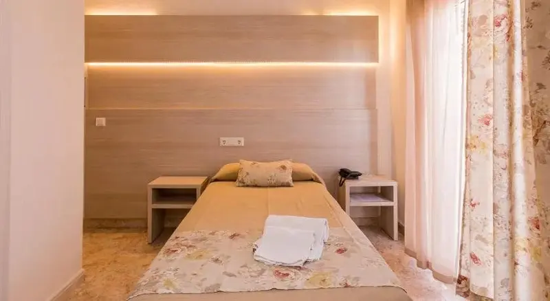 Une chambre lumineuse avec un lit fait et des tables de chevet.