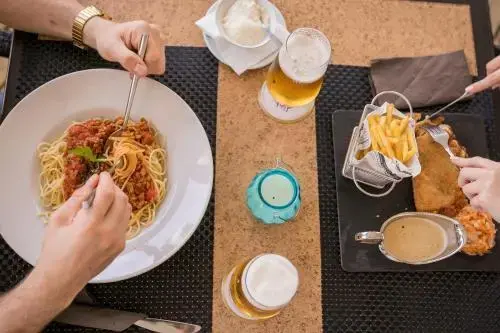 Une table est dressée avec des plats de pâtes et de frites.