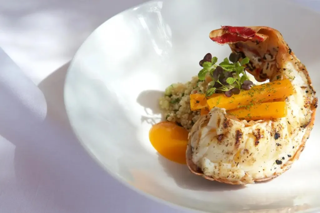 Présentation raffinée d'un plat de homard avec accompagnements.