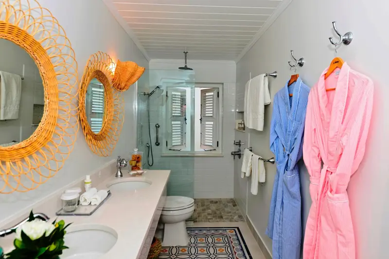 Une salle de bain lumineuse avec une douche à l'italienne et des peignoirs colorés.