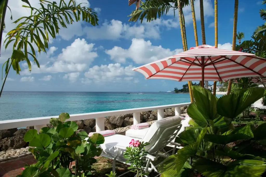 Transats et parasols rayés sur une terrasse ensoleillée avec vue sur la mer turquoise.