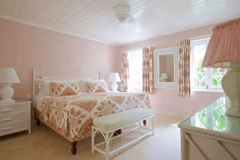 Une chambre lumineuse avec un grand lit recouvert d'une couette à motifs floraux.