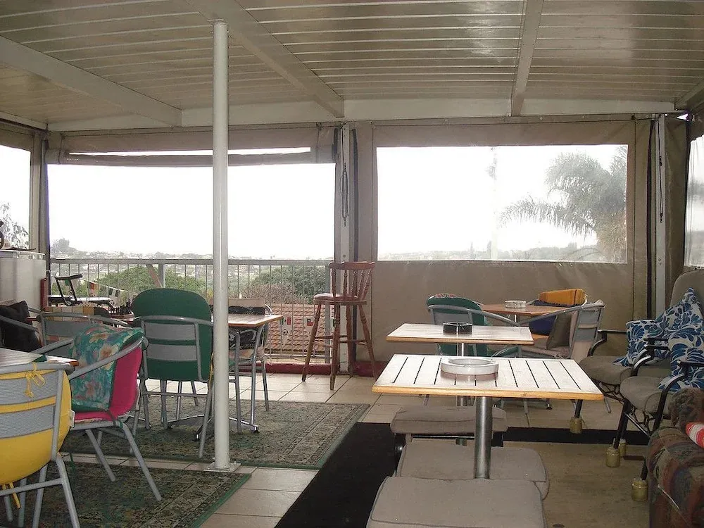 Espace de détente extérieur avec tables et chaises face à un paysage verdoyant.
