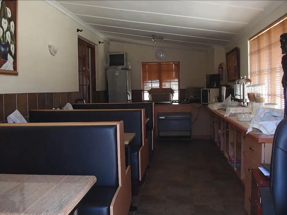 Une salle lumineuse avec des tables et des banquettes est aménagée pour les repas.