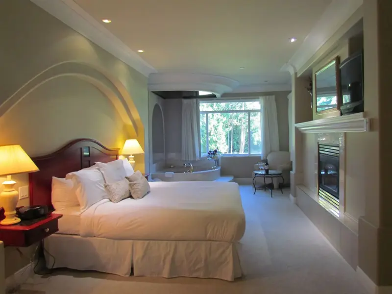 Une chambre spacieuse avec un grand lit et une baignoire près d'une fenêtre.