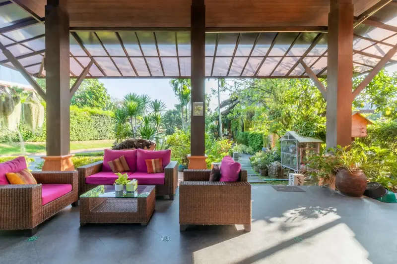 Espace de détente extérieur avec mobilier en rotin et végétation luxuriante.