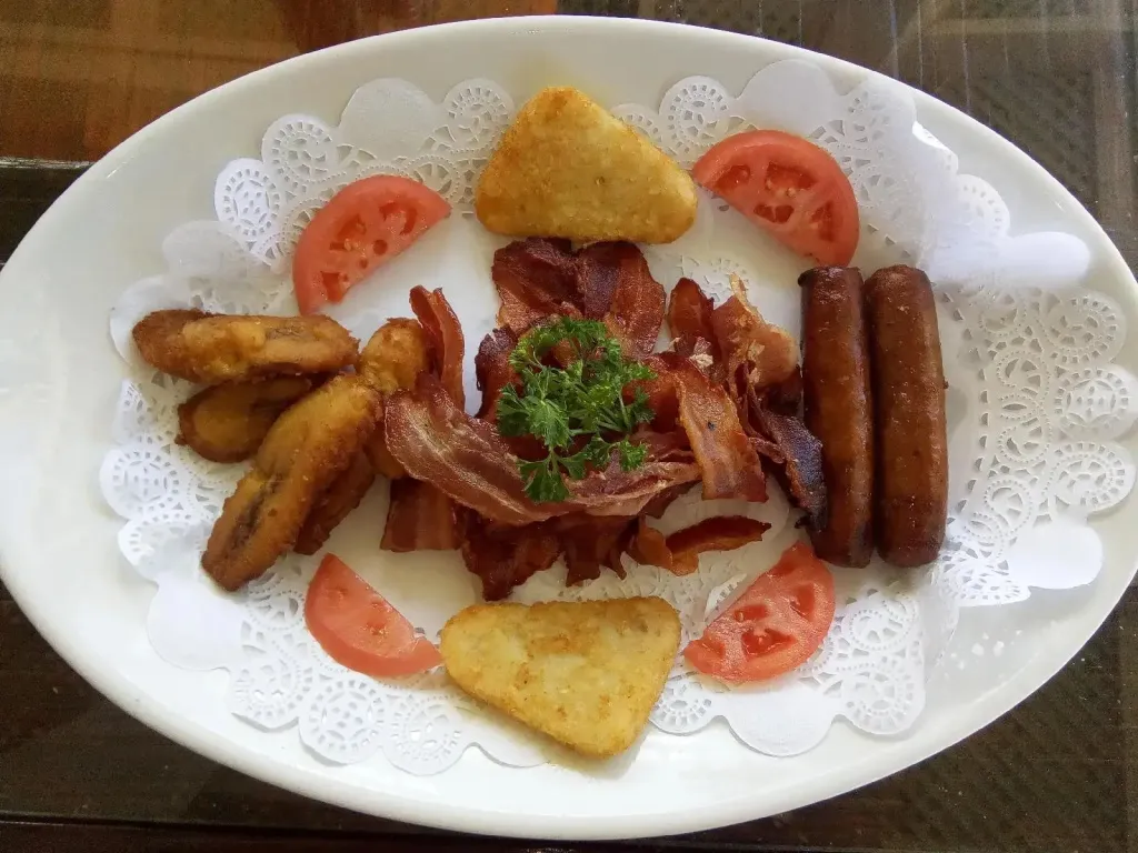 Assiette garnie de bacon, de saucisses, de pommes de terre et de tomates.