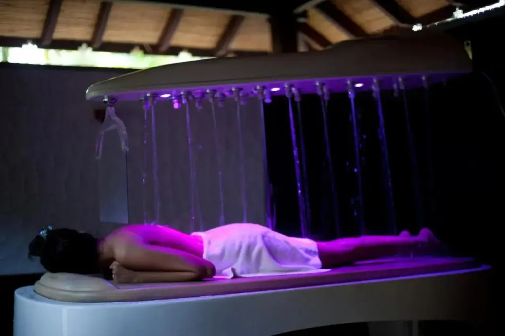 Une personne allongée sur une table de massage reçoit un soin aquatique.