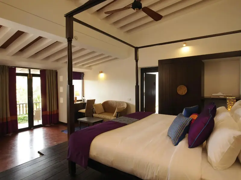Une chambre lumineuse avec un grand lit à baldaquin et un coin salon.
