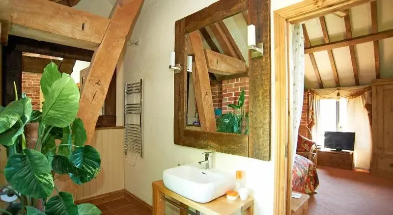 Une salle de bain rustique avec un grand miroir et des éléments en bois apparents.