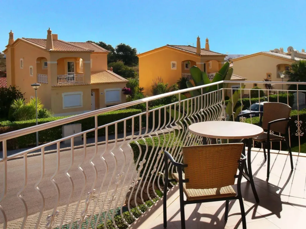 Terrasse ensoleillée avec mobilier de jardin et vue sur des bâtiments aux toits en tuiles.