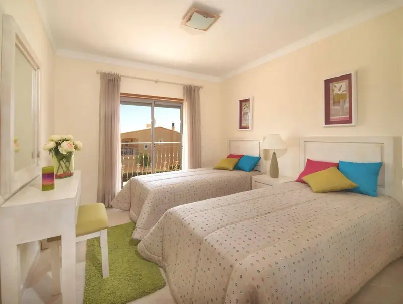 Une chambre lumineuse avec deux lits simples et une vue sur l'extérieur.
