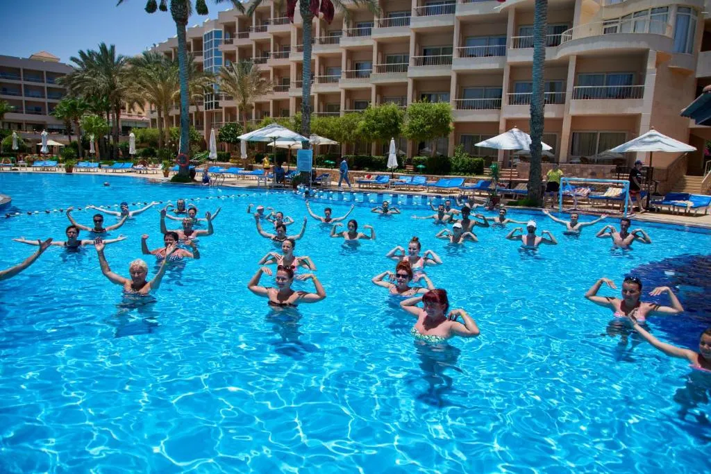 Un groupe de personnes participe à un cours d'aquagym dans une piscine ensoleillée.