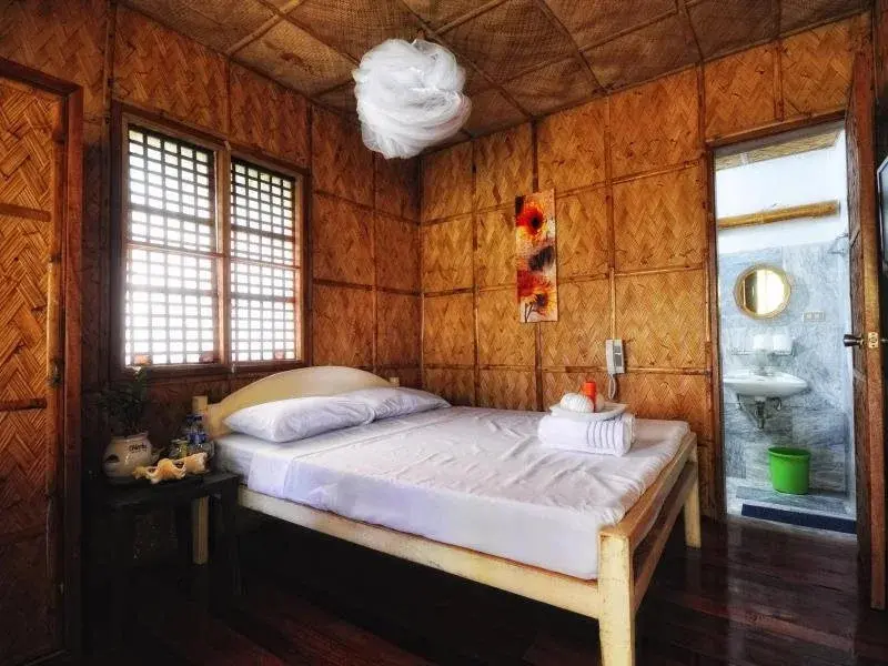 Une chambre lumineuse avec un lit recouvert de draps blancs et une salle de bain ouverte.