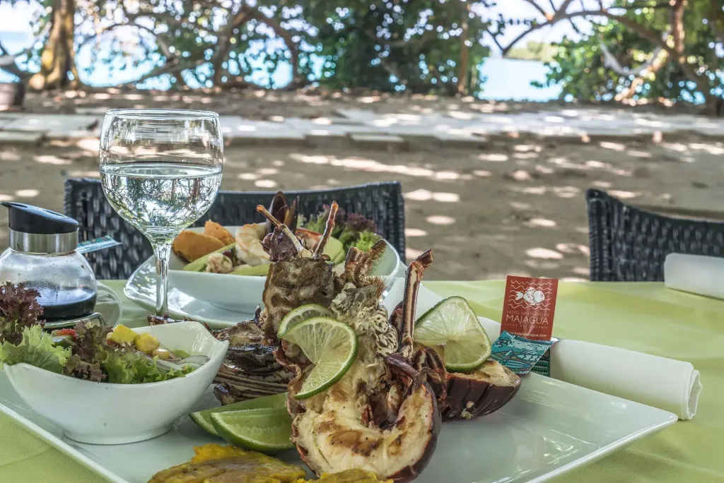 Une assiette de fruits de mer est présentée sur une table en extérieur face à la mer.