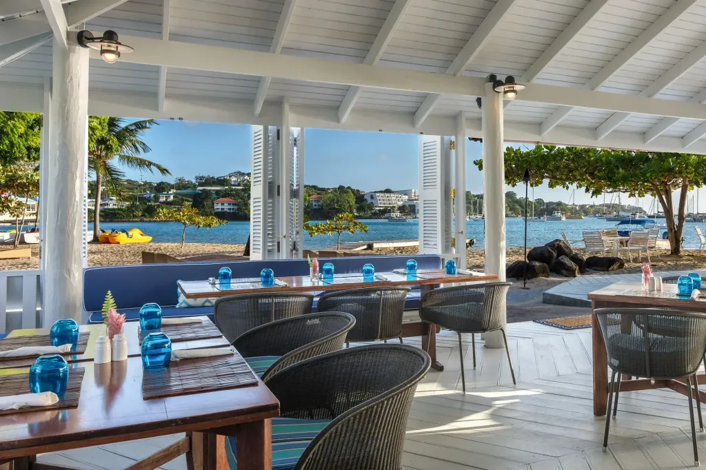 Tables et chaises disposées sous une structure ouverte donnant sur la mer.