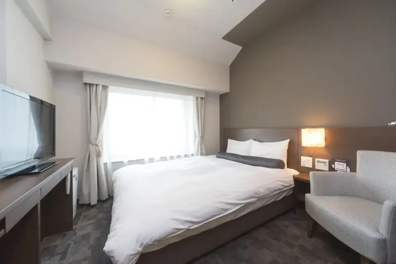Une chambre d'hôtel lumineuse avec un grand lit et un fauteuil.