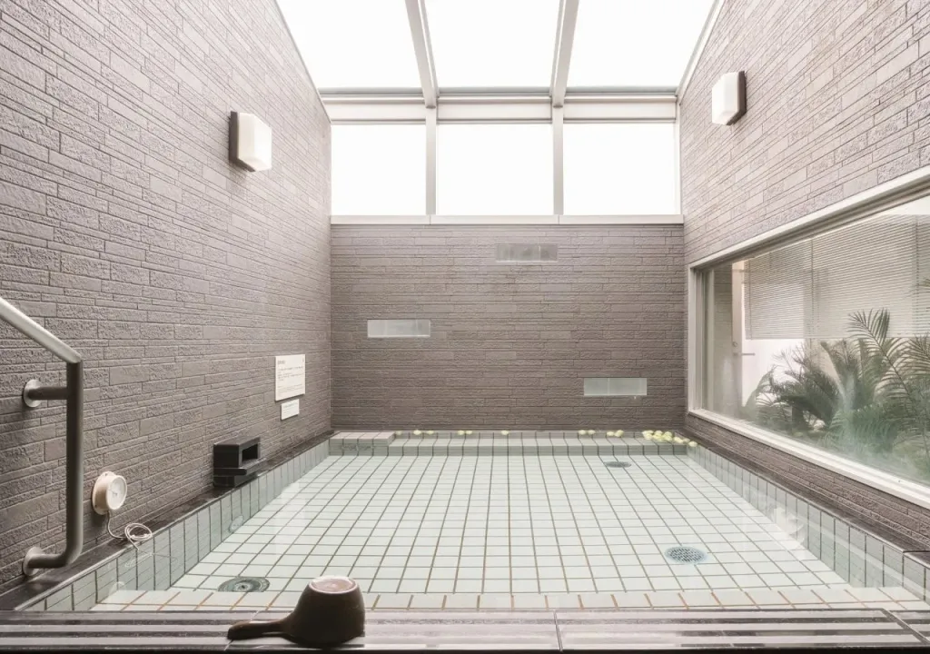 Une piscine interieure carree avec un mur de briques et une fenetre donnant sur la vegetation.