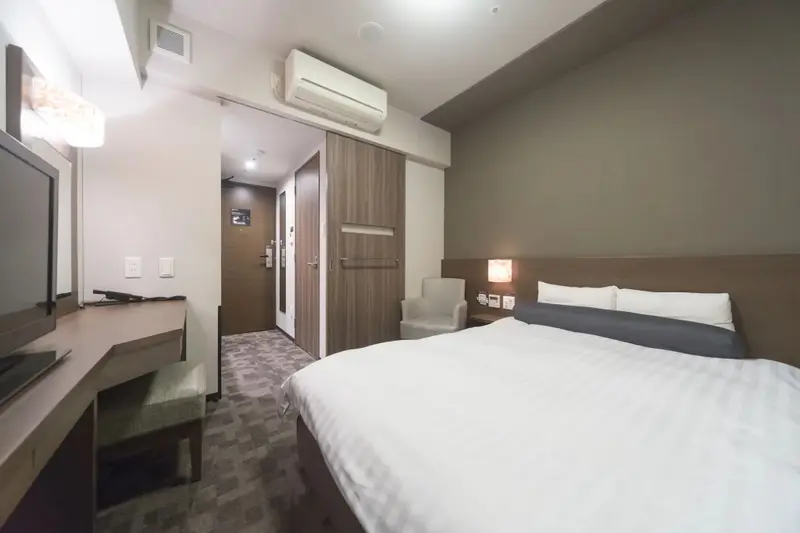 Une chambre d'hôtel lumineuse avec un lit fait et un espace bureau.