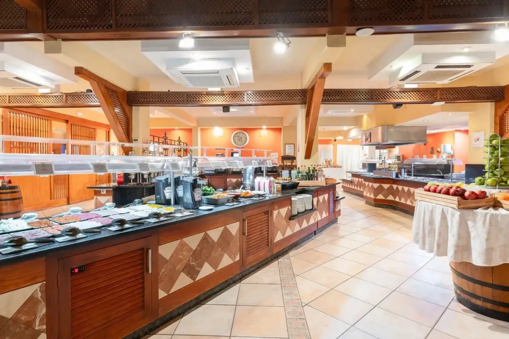 Un buffet propose une variété de plats et de fruits frais dans une salle lumineuse.