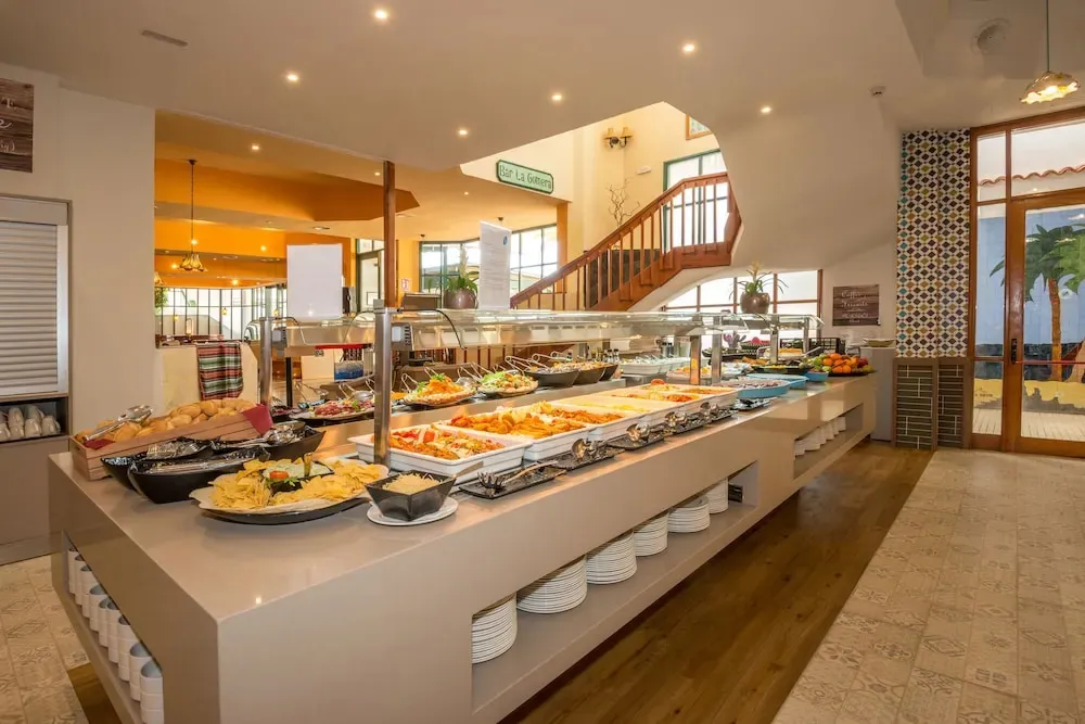 Un buffet propose une variété de plats et de salades dans une salle lumineuse.