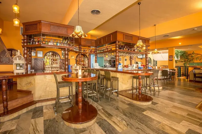 Un comptoir de bar en bois avec des tabourets et des bouteilles.