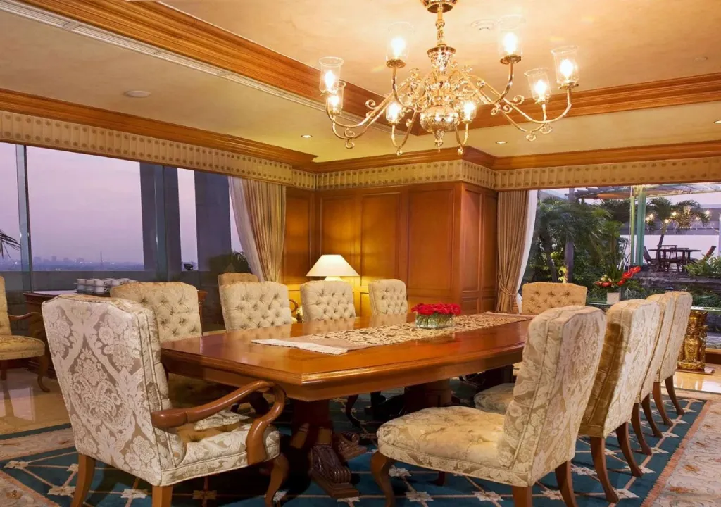 Une grande salle à manger lumineuse avec une longue table en bois et des chaises élégantes.