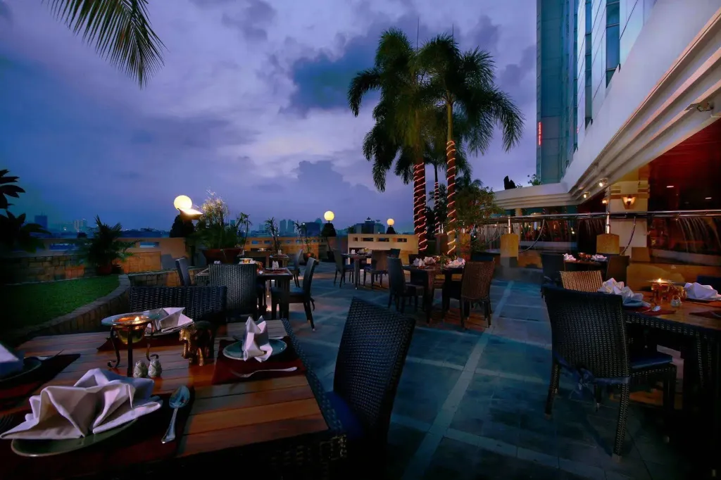 Tables dressées en terrasse avec vue sur la ville au crépuscule.
