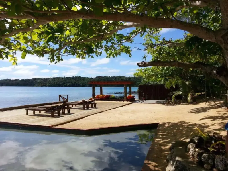 Terrasse en bois avec chaises longues au bord de l'eau.