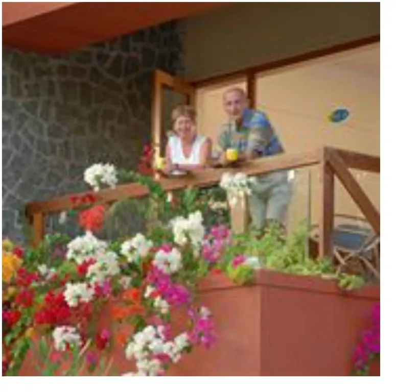Un couple se tient sur une terrasse fleurie.