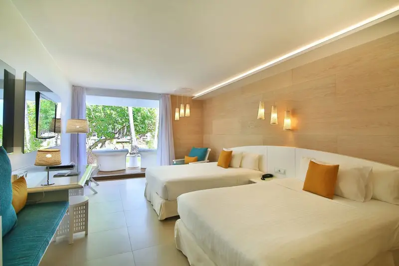 Une chambre lumineuse avec deux lits et un coin salon.