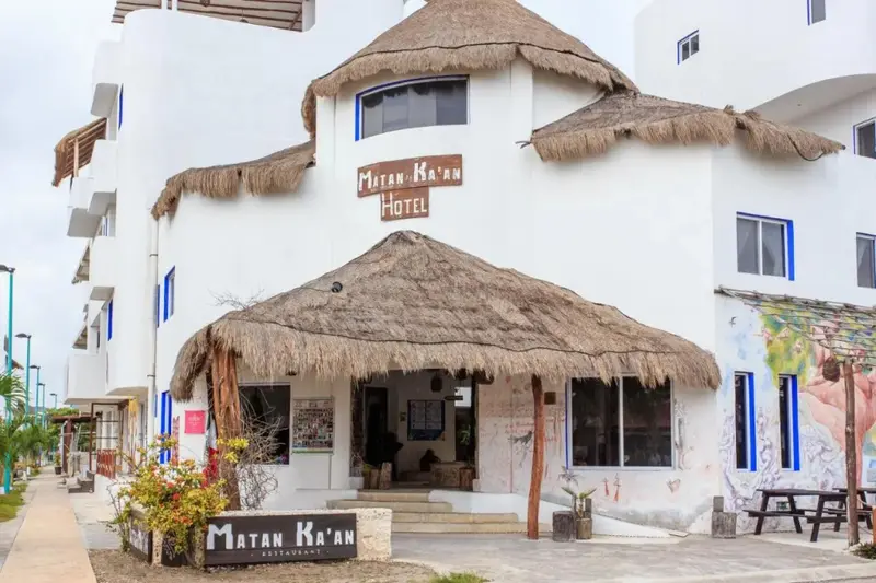 Façade d'un bâtiment blanc avec des toits de chaume et une entrée ombragée.