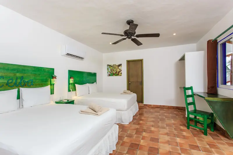 Une chambre lumineuse avec deux lits simples et un bureau vert.