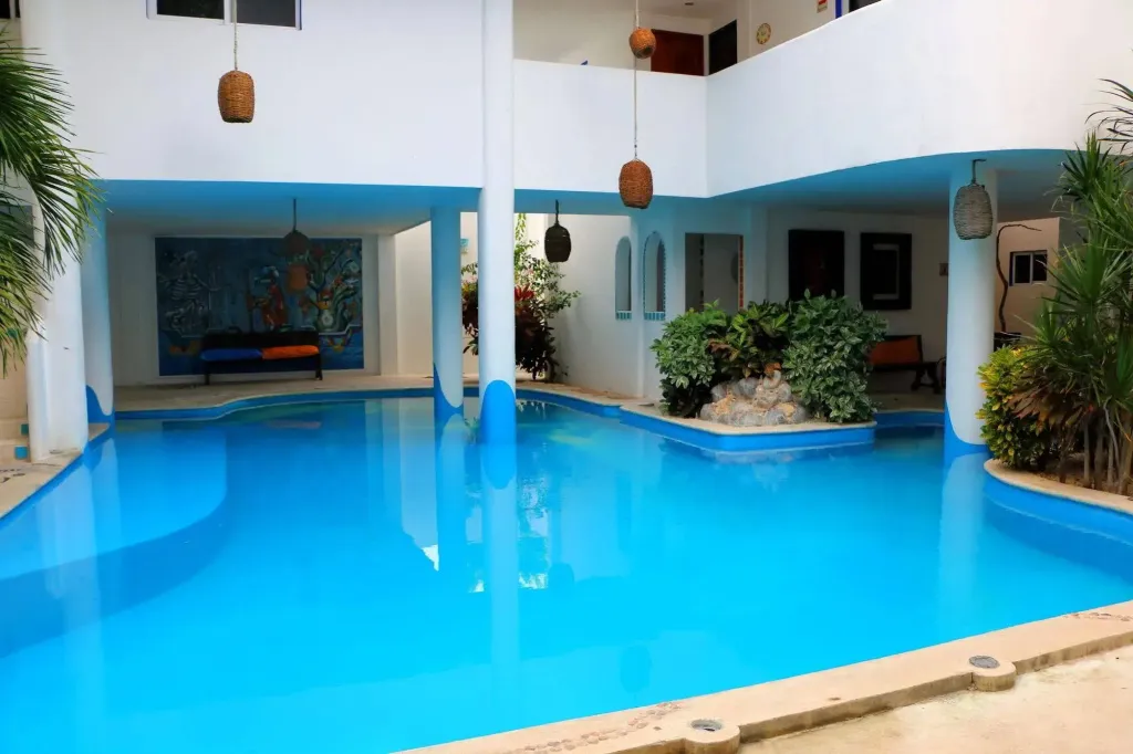 Piscine bleue entourée d'une architecture blanche et de végétation tropicale.