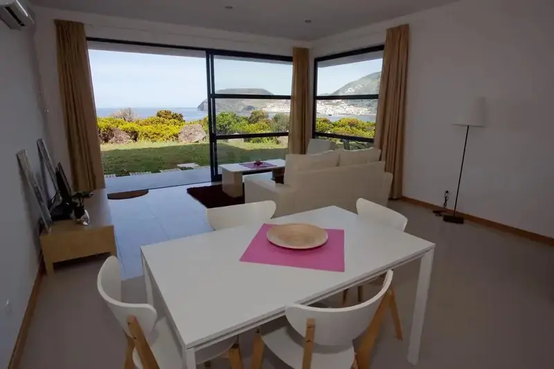 Espace de vie lumineux avec coin repas et vue sur un paysage côtier.