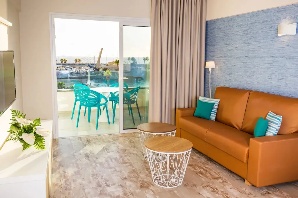 Un salon lumineux s'ouvre sur une terrasse avec vue sur un port de plaisance.