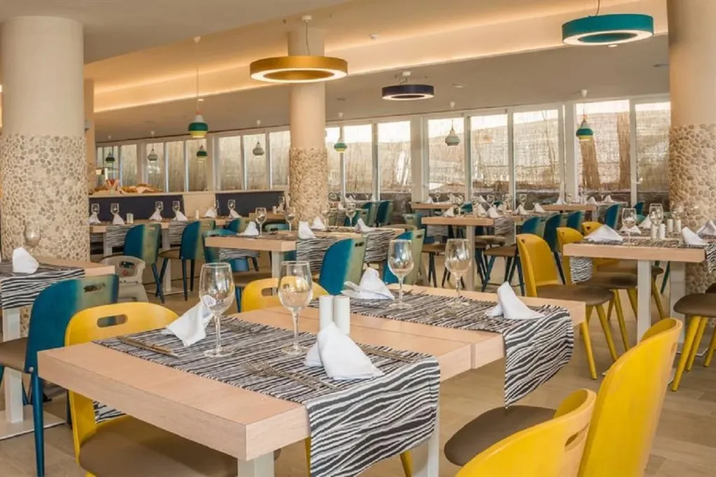 Une salle lumineuse avec des tables dressées pour le repas.