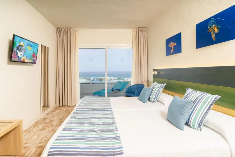 Une chambre lumineuse avec un grand lit donnant sur une vue mer.