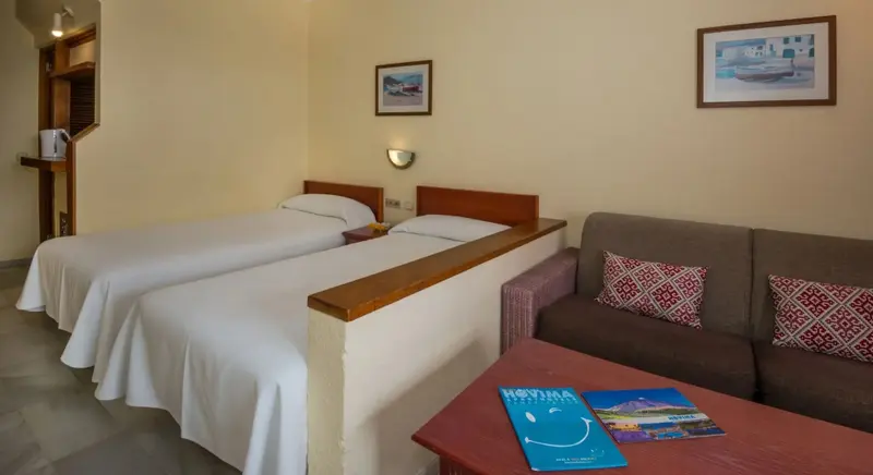 Une chambre lumineuse avec deux lits simples et un canapé.